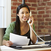 Asian woman on phone holding papers in an office